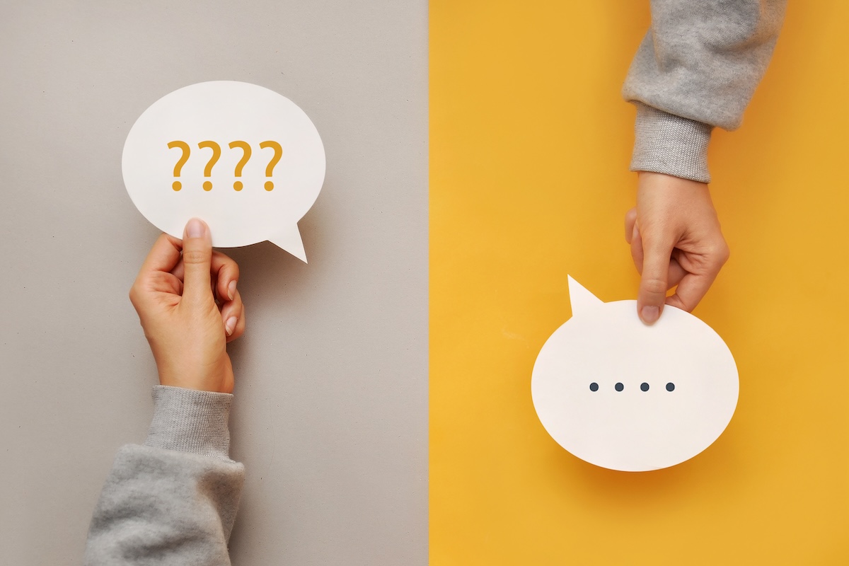 Deux mains tenant des bulles de dialogue, l’une avec des points d’interrogation et l’autre avec des points de suspension