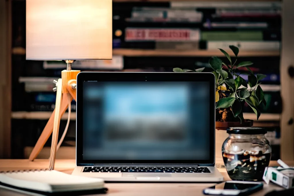 Ordinateur portable sur un bureau avec un carnet, une lampe et une plante